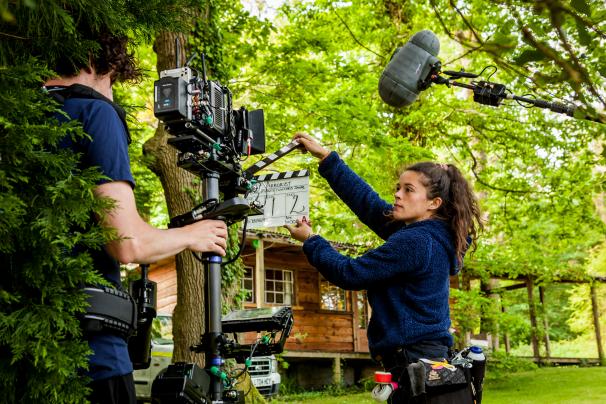 Man holding a camera and women holding a clapperboard in the forest. Credit: Arborist - Tom Sparey
