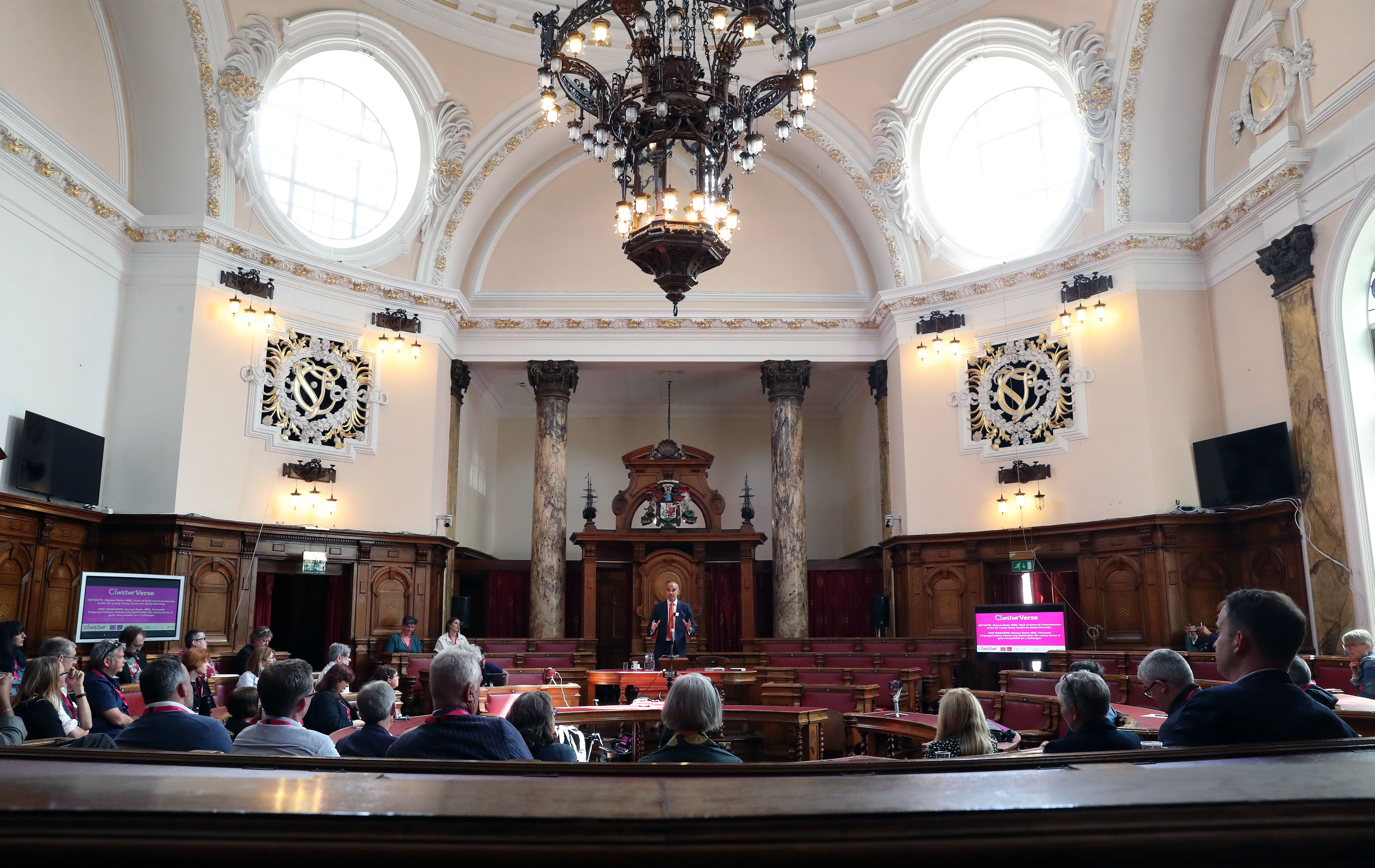 Marcus Ryder MBE presents to audience in the Council Chamber at Cardiff City Hall for ClwstwrVerse