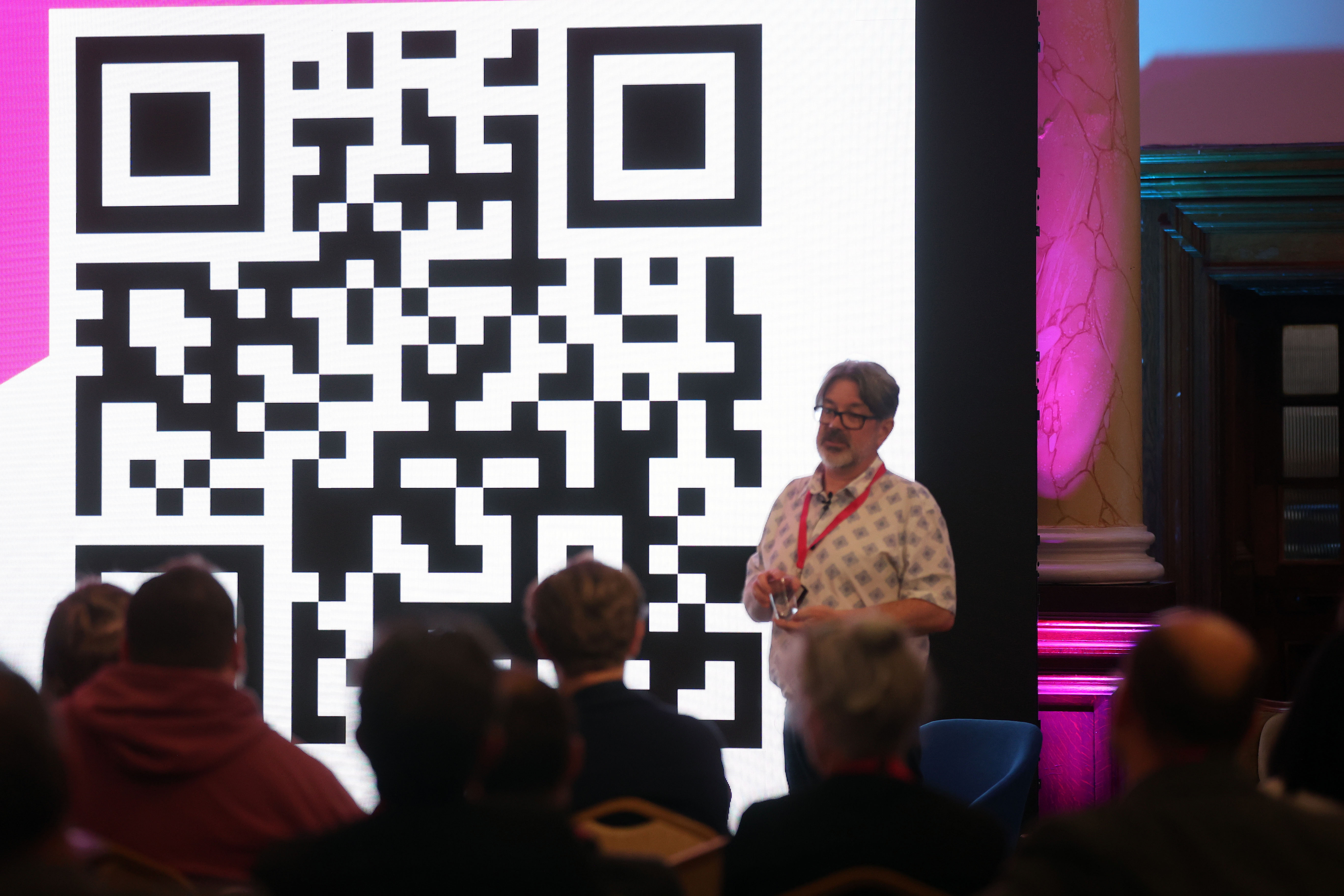 Robin Moore presents infront of a large screen featuring QR code