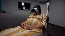 Pregnant women wearing VR headwear lying on hospital bed. 