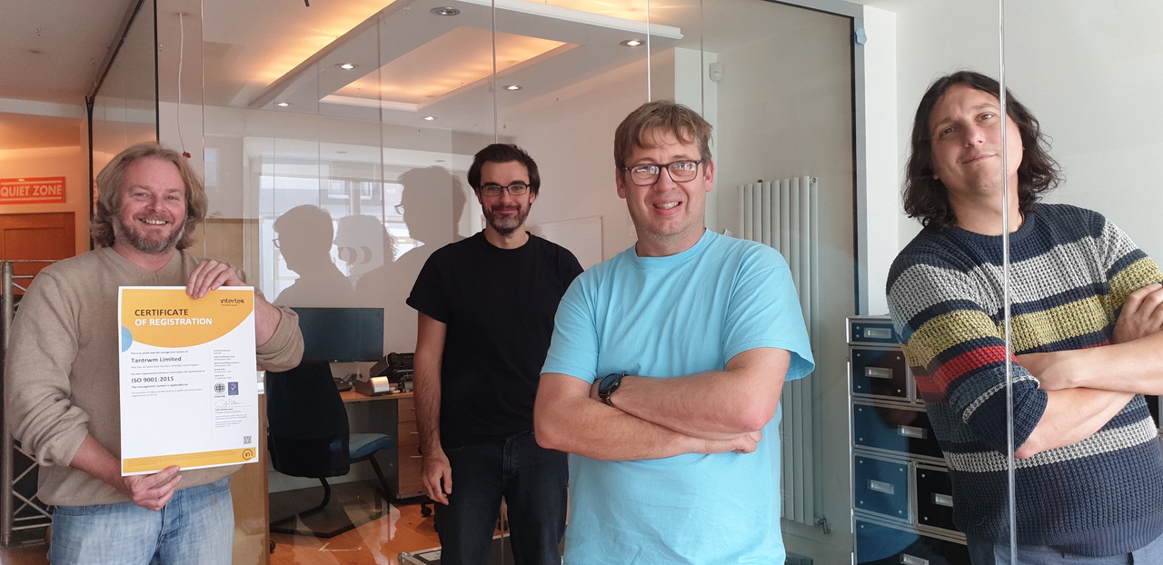 Tantrwm team photo - four male Tantrwm team members standing in an office facing the camera